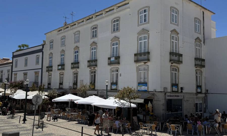 The row of houses on the Praça da República: four storeys with balconies and regular window bays above the café parasols. Own photo — Flemming Berthelsen, 2026.