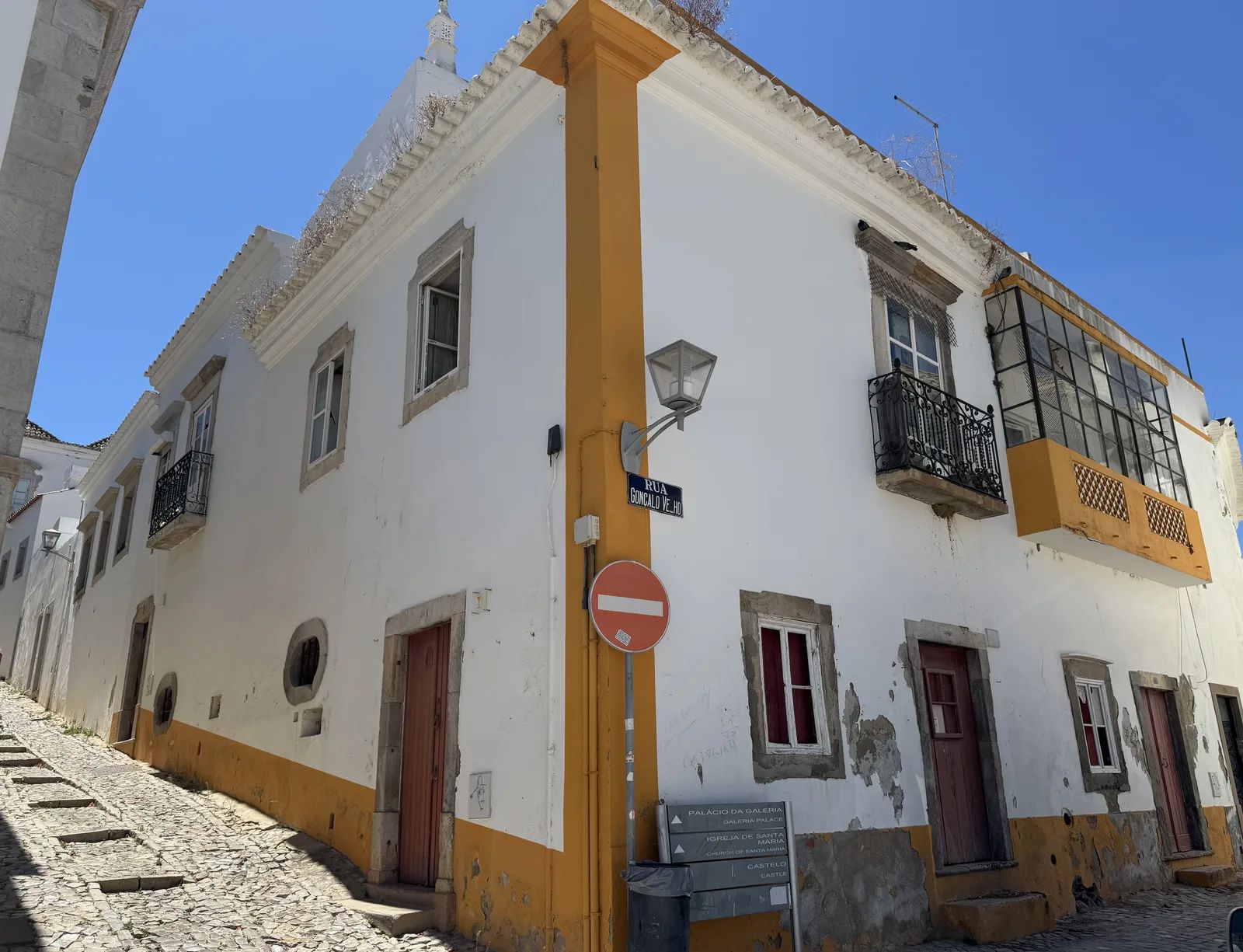 The corner house at Rua Gonçalo Velho and Calçada da Galeria: doors at street level and a balcony window with a stone surround on the floor above. Own photo — Flemming Berthelsen, 2026.