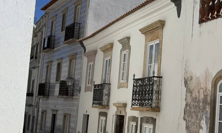 A narrow cobbled street by the church of Santiago: white façades with doors and single windows in rhythm down the street. Own photo — Flemming Berthelsen, 2026.